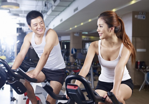 young man and woman talking while exercising on bicycle in fitness center. click for more: